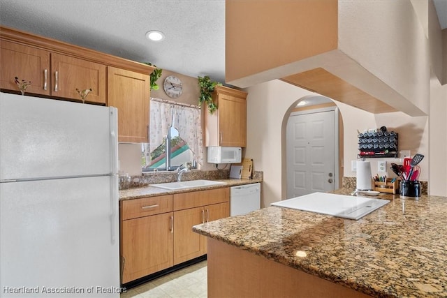 4845 Casablanca Cir Unit F23, Sebring, FL 33870 - kitchen featuring white appliances, a sink, arched walkways, light stone countertops, and a peninsula