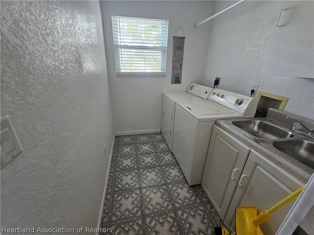 clothes washing area with cabinets, sink, and washer and dryer