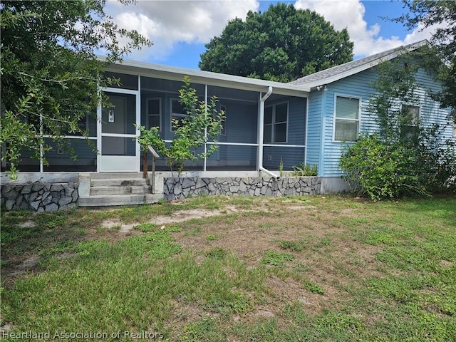 view of front of home with a sunroom and a front lawn