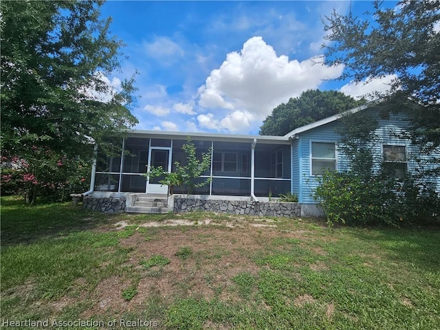 rear view of property featuring a sunroom and a yard