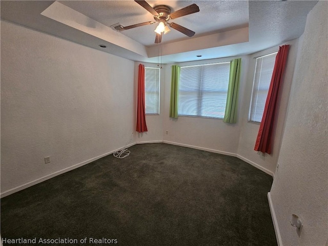 carpeted spare room with a tray ceiling, ceiling fan, and a textured ceiling