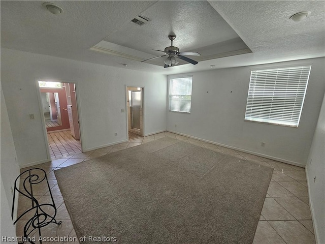 spare room with ceiling fan, light tile patterned flooring, and a tray ceiling