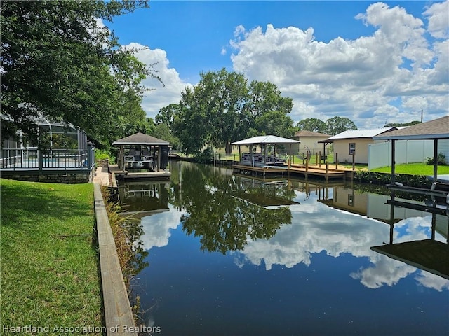 view of dock with a gazebo, a water view, and a lawn