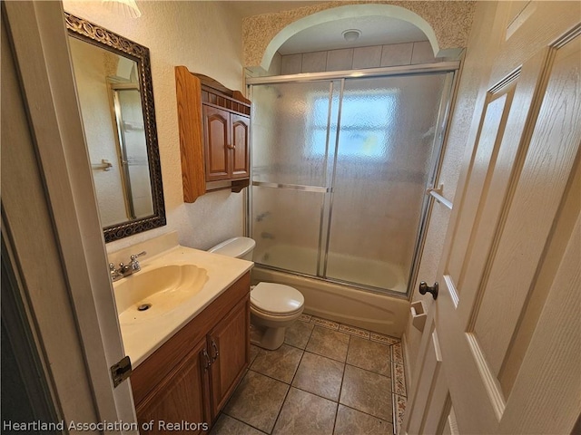 full bathroom featuring tile patterned flooring, vanity, bath / shower combo with glass door, and toilet