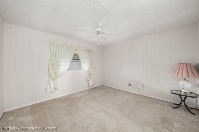 empty room featuring light colored carpet, a textured ceiling, and ceiling fan