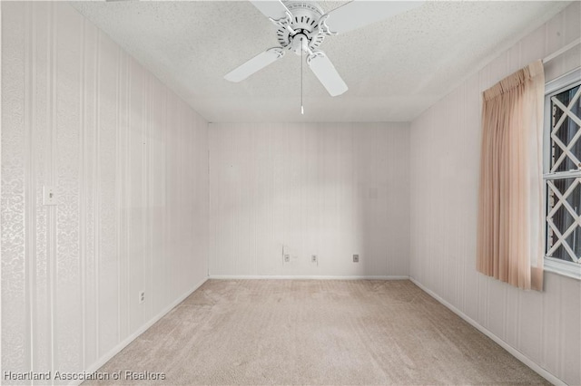 empty room with ceiling fan, light colored carpet, and a textured ceiling