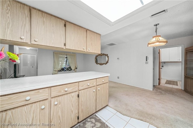 kitchen with pendant lighting, light colored carpet, a skylight, and light brown cabinets