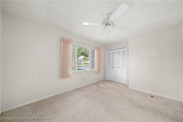 unfurnished bedroom with light carpet, ceiling fan, a closet, and a textured ceiling