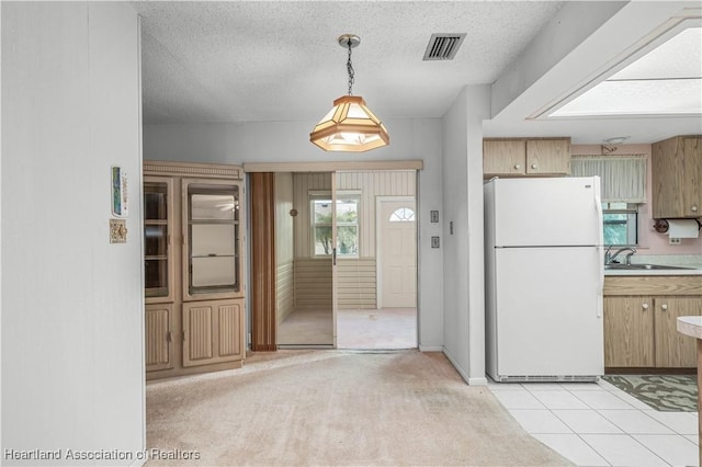 kitchen featuring pendant lighting, sink, a textured ceiling, light colored carpet, and white fridge