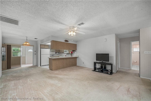 unfurnished living room with ceiling fan, sink, light carpet, and a textured ceiling