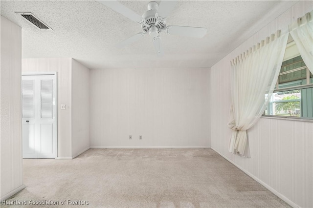 carpeted spare room featuring ceiling fan and a textured ceiling