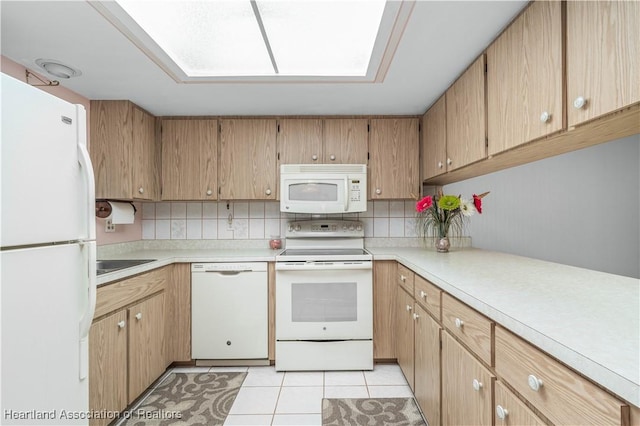 kitchen with sink, light tile patterned floors, white appliances, a skylight, and decorative backsplash