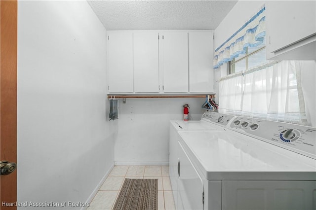 laundry room featuring cabinets, light tile patterned floors, washer and dryer, and a textured ceiling