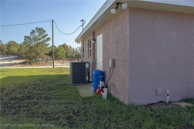 view of property exterior featuring central air condition unit and a lawn