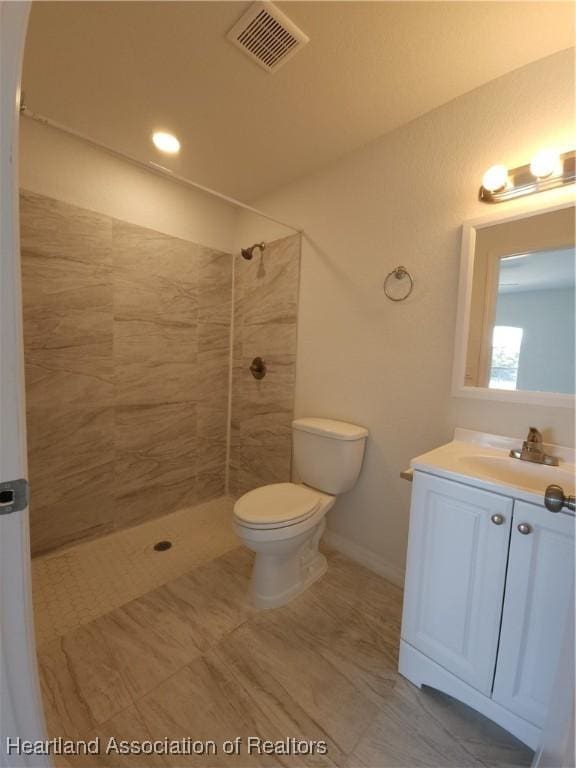 bathroom featuring tiled shower, vanity, and toilet