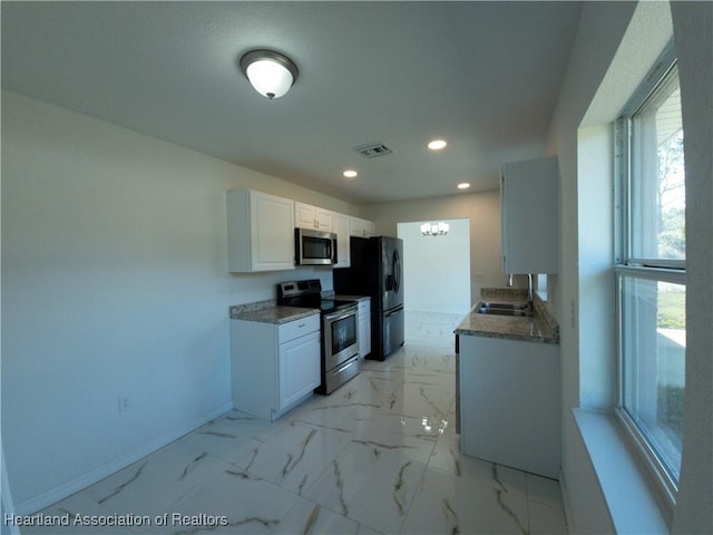 kitchen featuring white cabinetry, sink, a chandelier, and appliances with stainless steel finishes