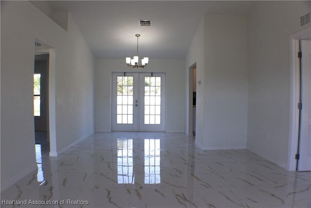 empty room featuring a chandelier and french doors