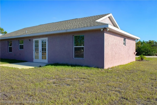 rear view of property featuring french doors, a patio area, and a lawn