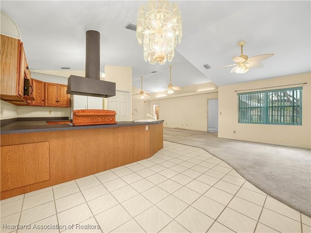 kitchen featuring vaulted ceiling, island range hood, hanging light fixtures, light colored carpet, and kitchen peninsula