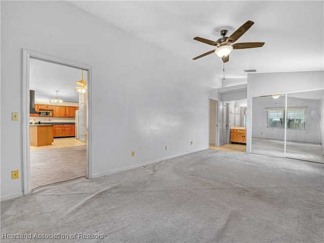 unfurnished bedroom featuring ceiling fan, light colored carpet, lofted ceiling, and ensuite bath