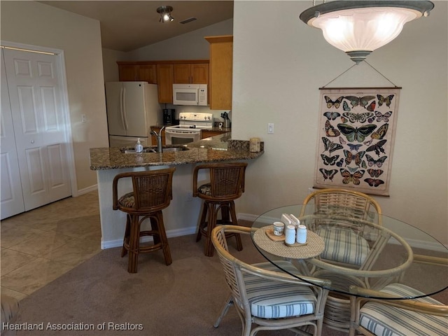 dining area featuring light tile patterned floors, sink, and vaulted ceiling