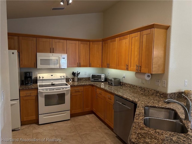 kitchen featuring white appliances, high vaulted ceiling, sink, dark stone countertops, and light tile patterned floors