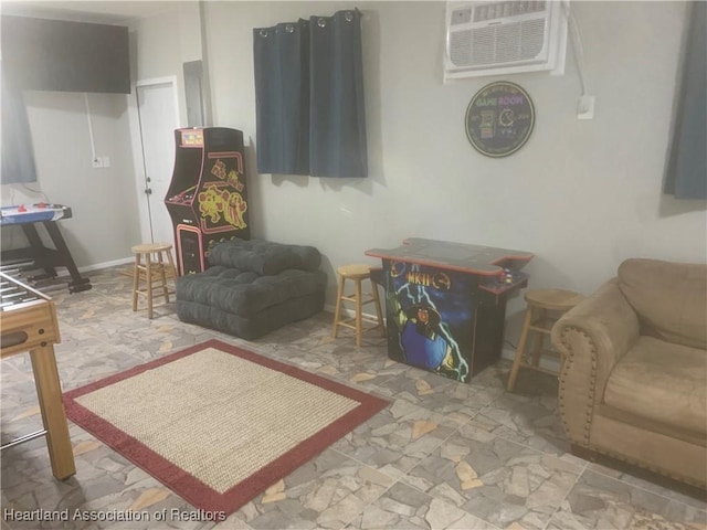 living area with baseboards and an AC wall unit