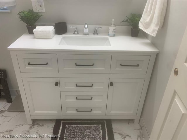 bathroom with marble finish floor, vanity, and baseboards