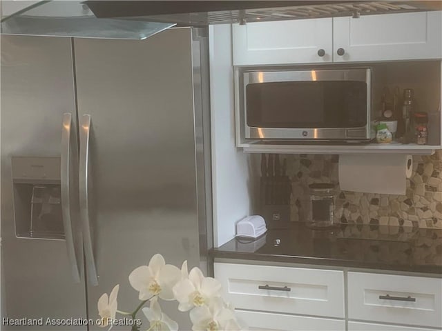 kitchen with stainless steel appliances, dark countertops, white cabinets, and decorative backsplash