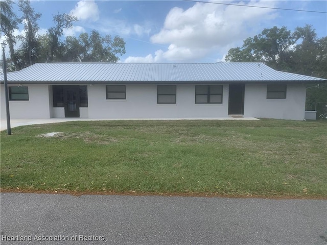 back of property featuring metal roof, a lawn, and stucco siding