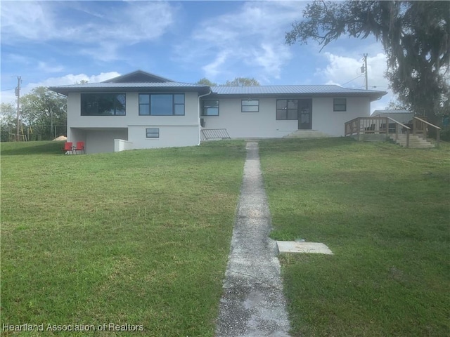 view of front of property with metal roof, a front yard, and stucco siding