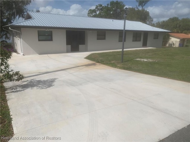 ranch-style home featuring a front yard, metal roof, concrete driveway, and stucco siding