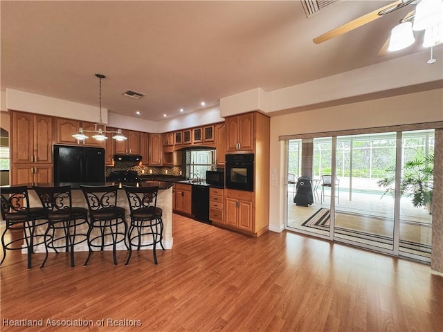 5717 Longbow Dr, Sebring, FL 33876 - kitchen with black appliances, dark countertops, a breakfast bar, brown cabinetry, and recessed lighting