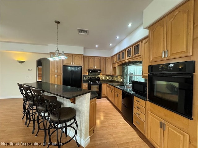 5717 Longbow Dr, Sebring, FL 33876 - kitchen featuring black appliances, a kitchen breakfast bar, a kitchen island, light wood-style floors, and recessed lighting