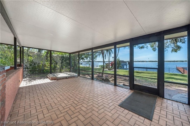 unfurnished sunroom featuring a water view