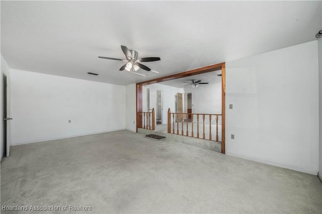 empty room featuring carpet, ceiling fan, and beamed ceiling