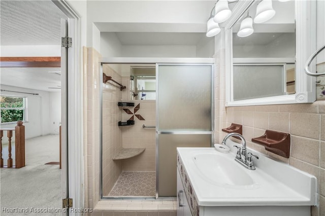 bathroom featuring decorative backsplash, a shower with door, and vanity