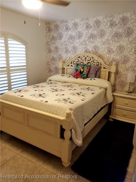 6401 Matanzas Dr, Sebring, FL 33872 - bedroom featuring wallpapered walls, light tile patterned floors, and a ceiling fan