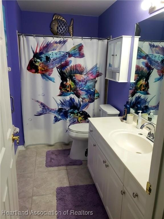 6401 Matanzas Dr, Sebring, FL 33872 - full bath featuring toilet, tile patterned flooring, vanity, and a shower with shower curtain