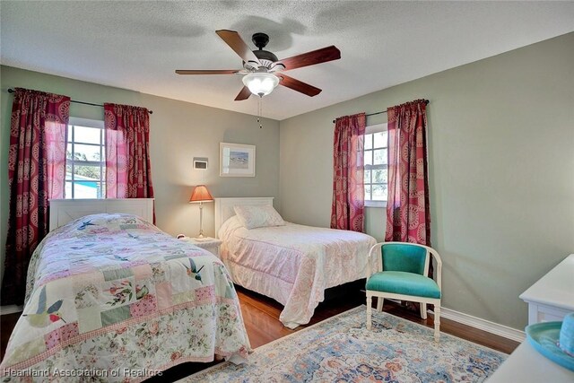 bedroom featuring multiple windows, hardwood / wood-style floors, a textured ceiling, and ceiling fan