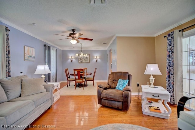 living room with ceiling fan with notable chandelier, a textured ceiling, light hardwood / wood-style flooring, and plenty of natural light