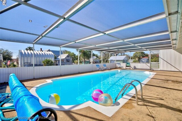 view of swimming pool featuring a patio and glass enclosure