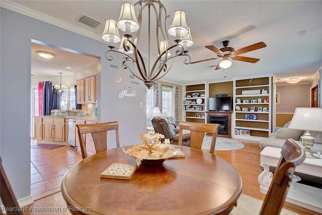 dining room with ceiling fan with notable chandelier, built in features, ornamental molding, a textured ceiling, and light tile patterned floors