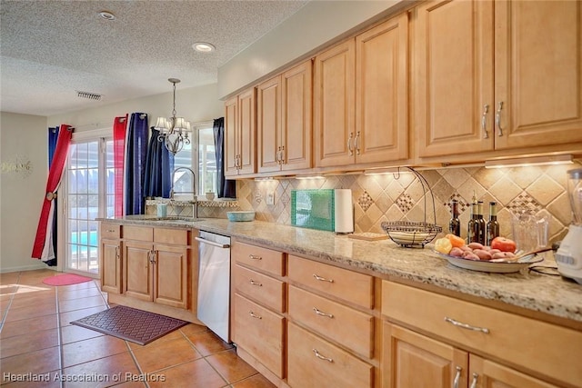 kitchen with light brown cabinetry, light stone countertops, sink, and hanging light fixtures