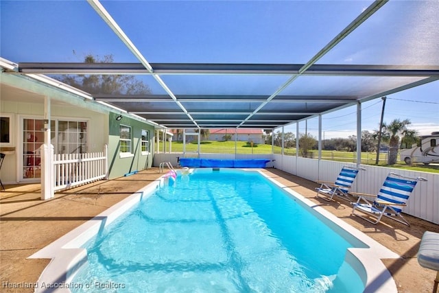 view of swimming pool featuring glass enclosure and a patio area