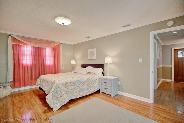 bedroom featuring hardwood / wood-style floors, a textured ceiling, and ornamental molding