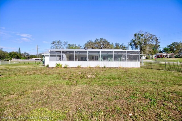 back of house with glass enclosure and a lawn