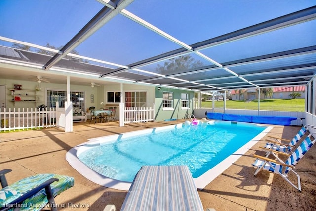 view of pool with glass enclosure, ceiling fan, and a patio area