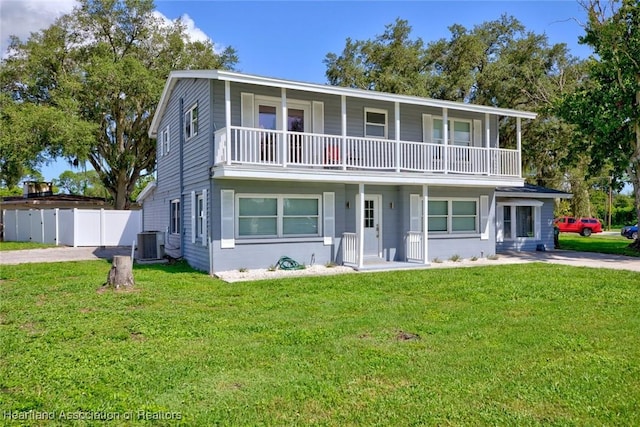 view of front of home with a balcony, cooling unit, and a front yard