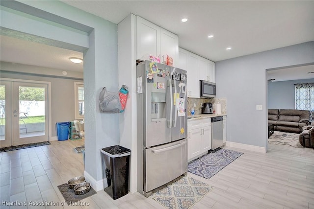 kitchen featuring stainless steel appliances, white cabinets, french doors, light hardwood / wood-style floors, and decorative backsplash